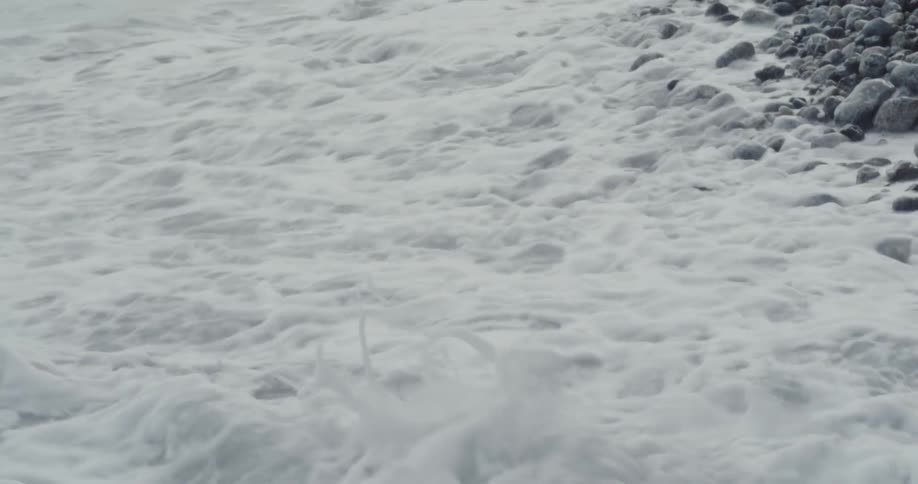 Waves crashing onto rocky shoreline with black rocks