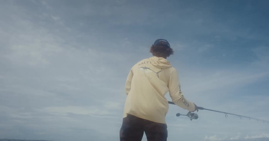 Person in cap fishing in ocean