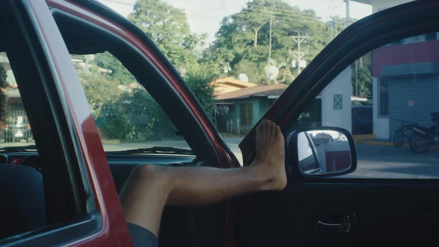 Man sitting in the front seat of a vehicle with his leg resting on the door
