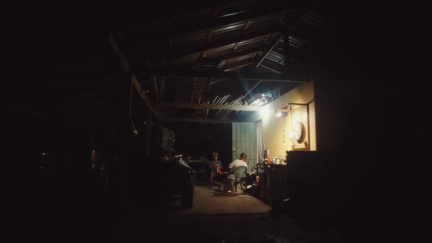 Two men sitting outside their house at night