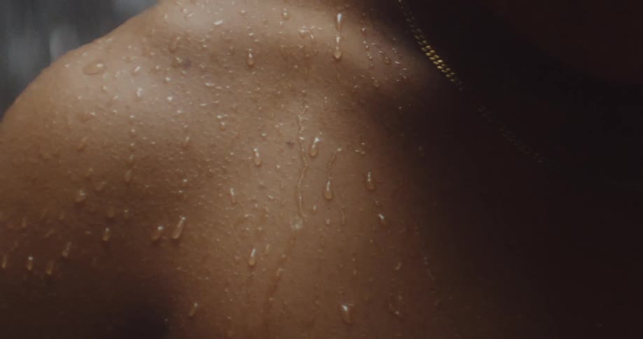 Person with damp skin stands near falling water