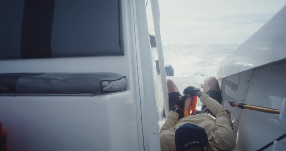 A man lays in boat holding a fishing reel