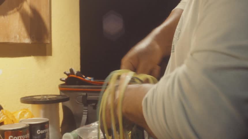 A person is working with a bundle of multicolored electrical wires using a screwdriver