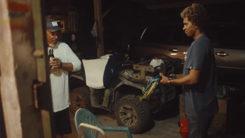 Two people handling colorful wires near an atv in a garage