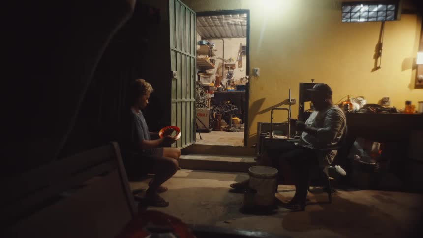 Two men are working with wire as they sit outside