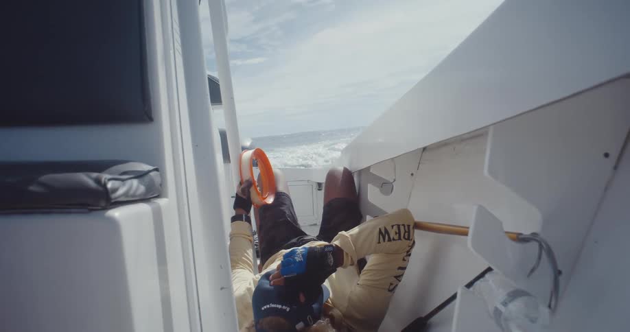 A man is holding a fishing line while laying down on the boat