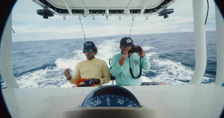 A man looks around with binoculars on the boat
