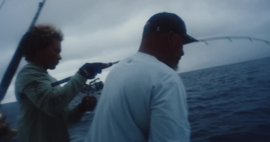 Two men in a boat in the middle of the ocean fishing