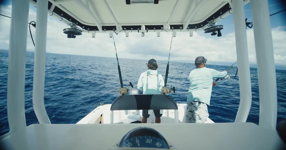 Father and son fish on a boat on the ocean on a cloudy day