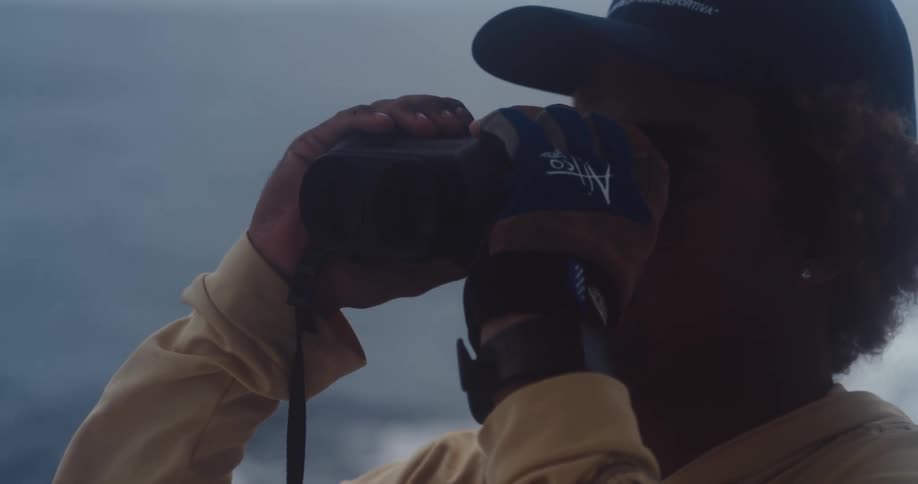 Young man looking through binoculars while on a boat at sea