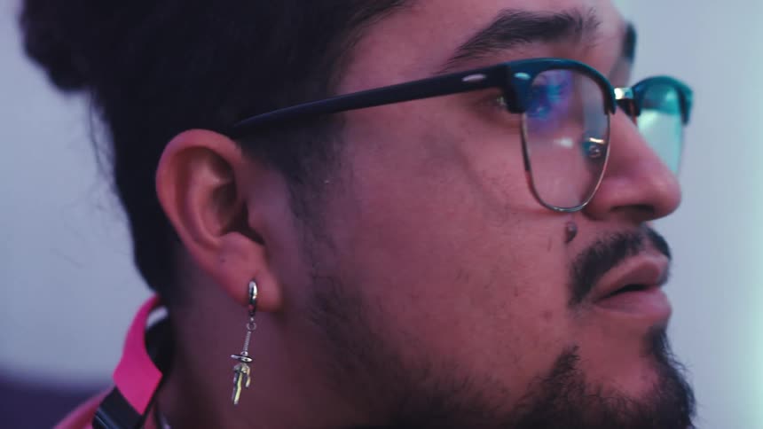 A man wearing headphones around his neck si playing video games at home