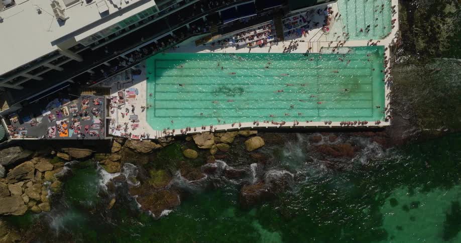 People are all around the pool by the shore
