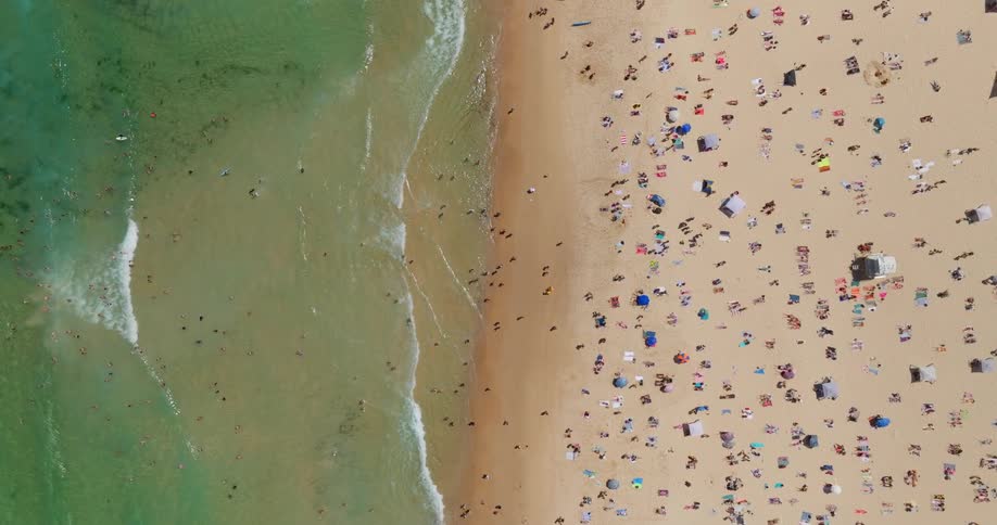 Birds eye view of a crowded beach with people on the sand and in the water