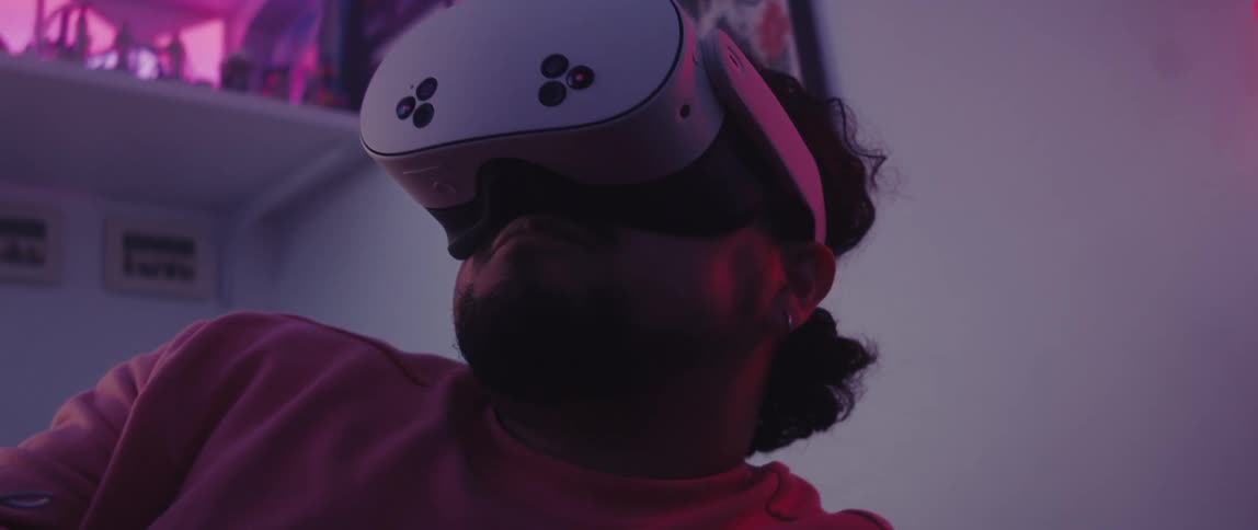 A man is wearing a virtual reality mask and interacting with something by pushing a button on a stick in his hand