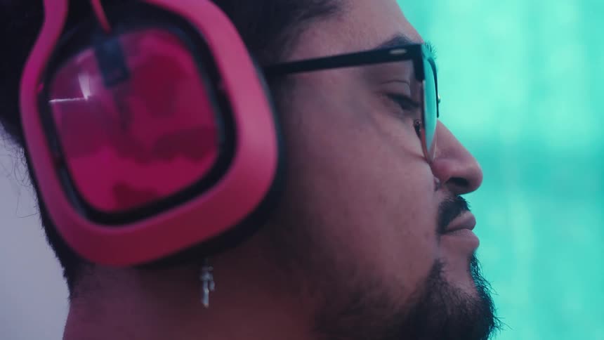 A person is wearing red and black overear headphones and a small silver earring shaped like a cross