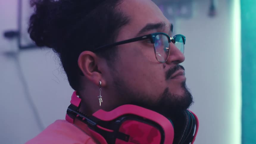 Man sitting at home in front of computer setup puts on his headphones