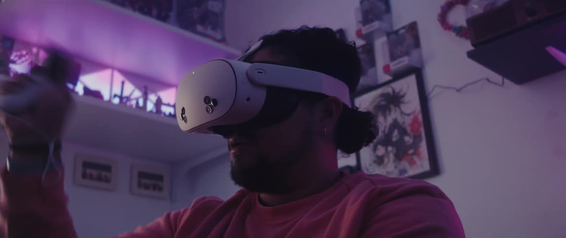 A person wearing a virtual reality headset interacts with a vr controller in a room decorated with anime posters action figures and shelves illuminated by pink lighting