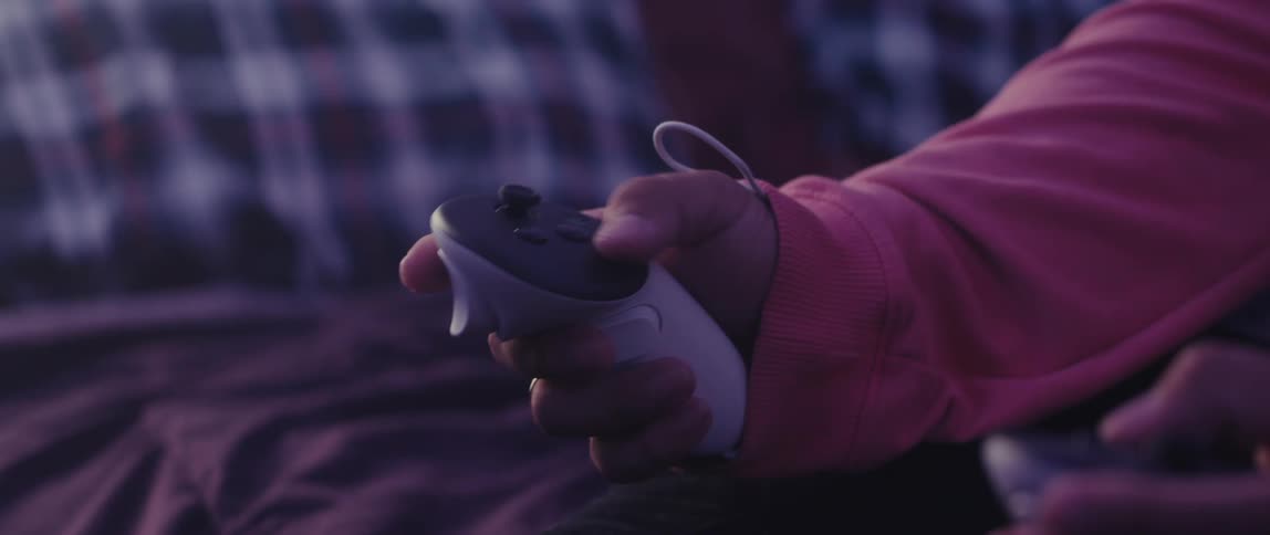 A person holds a white video game remote control in their hand