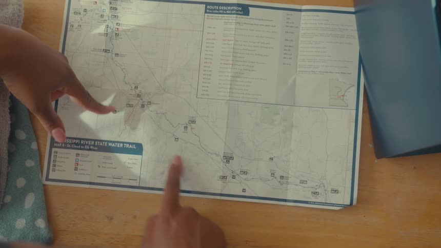 Two hands point at different locations on a detailed map of the mississippi river state water trail