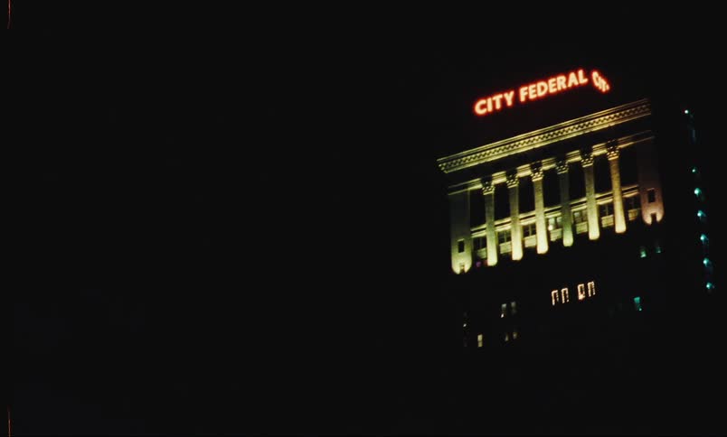 A night view of a tall building with illuminated signage at the top