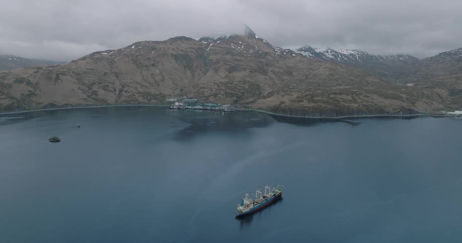 Aerial panorama of a boat isolated on a peninsula surrounded by snowy mountains