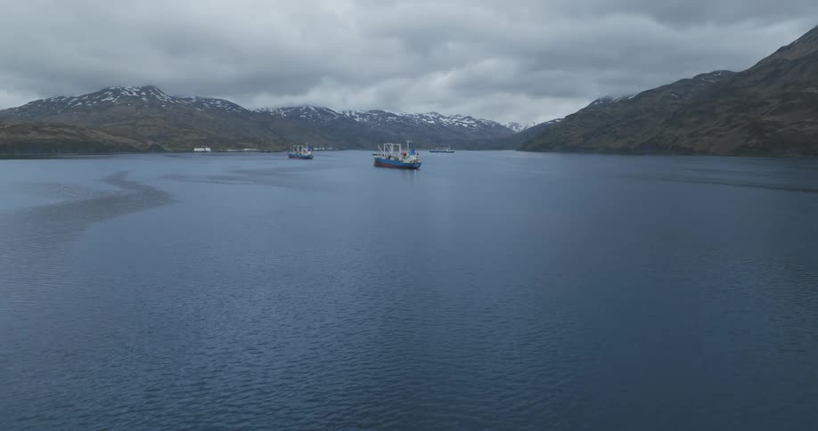 Aerial panorama of a ship in a sea surrounded by snowy mountains
