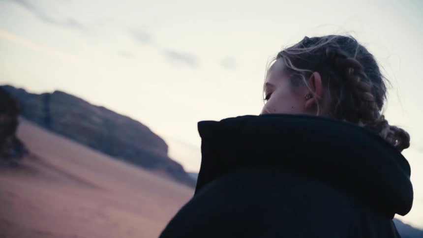 Woman with a happy facial expression walking through a desert environment with canyons in the background