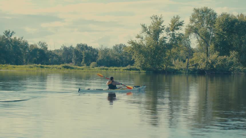 Person canoeing on a calm river during the day