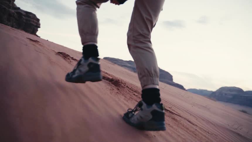 Legs of a person walking up the desert sand