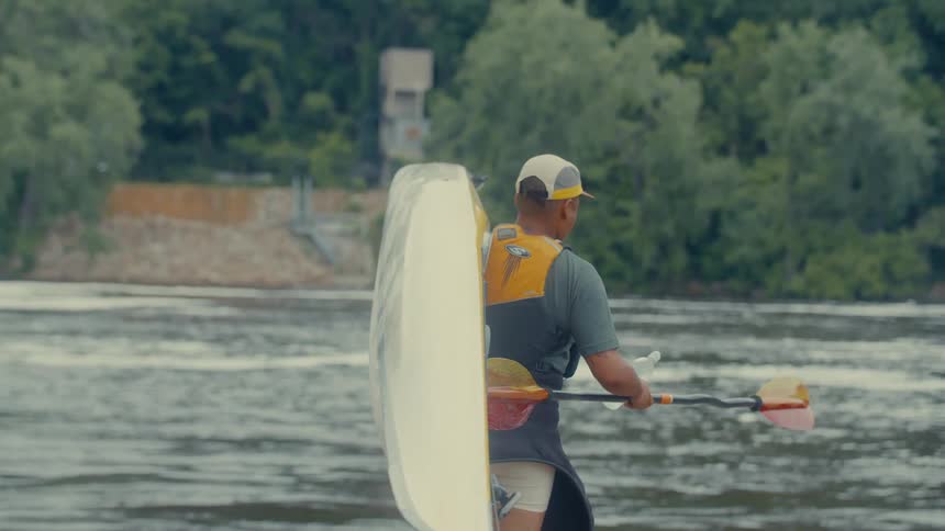 A person carries a kayak to the lake