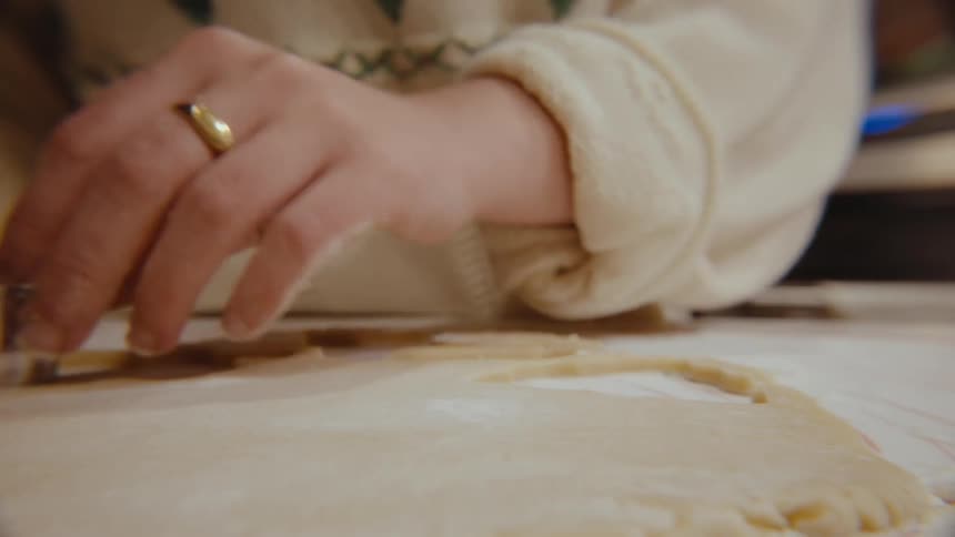Pair of hands cooking and cutting with a mold a dough