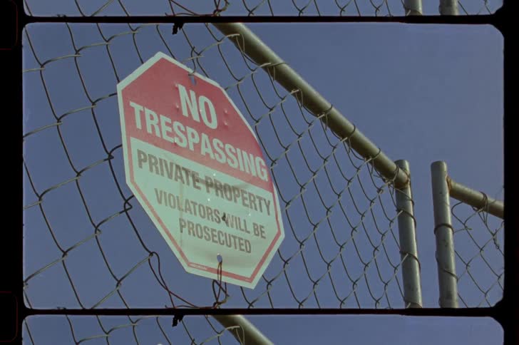 A no trespassing sign hangs on a chainlink fence