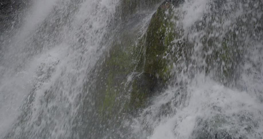 Moss covered rocks are battered by the relentless force of the falling water