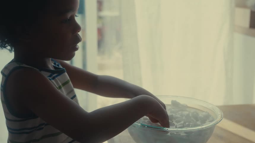 A child dunks their fingers in a bowl of ice water