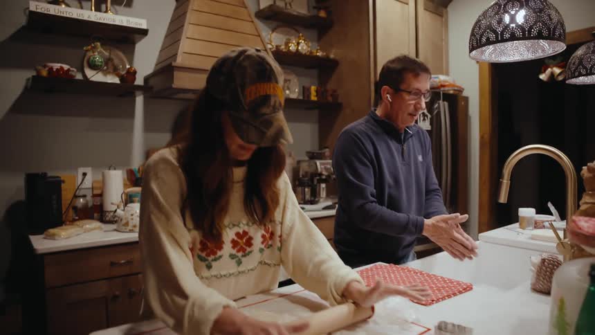 Woman next to a man in the kitchen preparing dough with a rolling pin