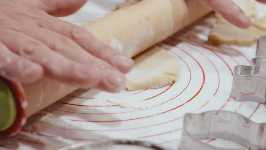 Man stands in the kitchen rolling out cookie dough