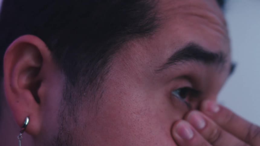 Portrait of a man rubbing his eyes in a worried manner