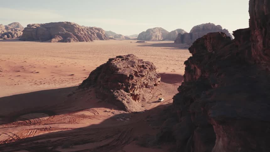 The top of a cliff is shown with the ground being all dirt and some large scattered rocks