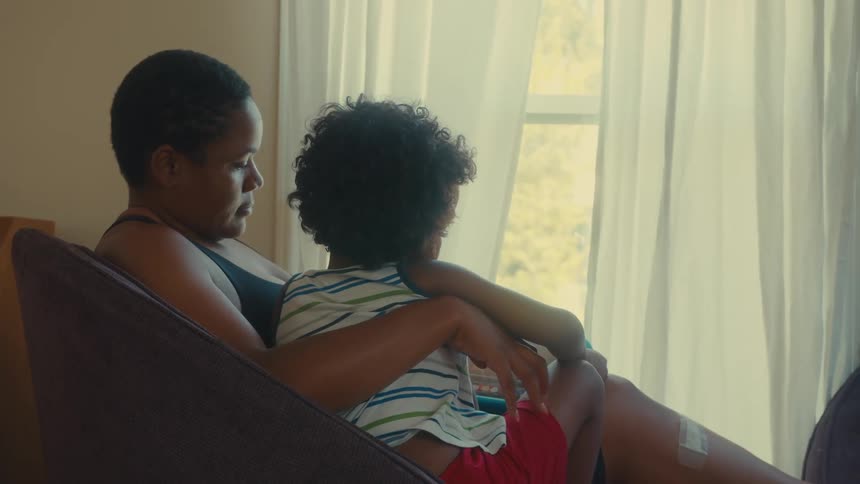 Mother sitting with her little son on her lap next to a window