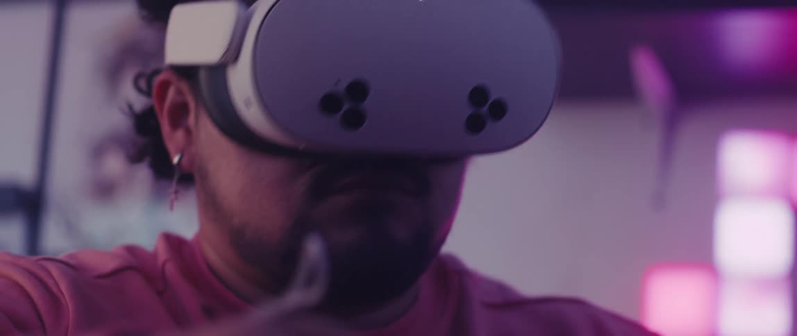 A man wearing a virtual reality headset and holding a controller immersed in a vr experience with dim lighting and a purple glow in the background