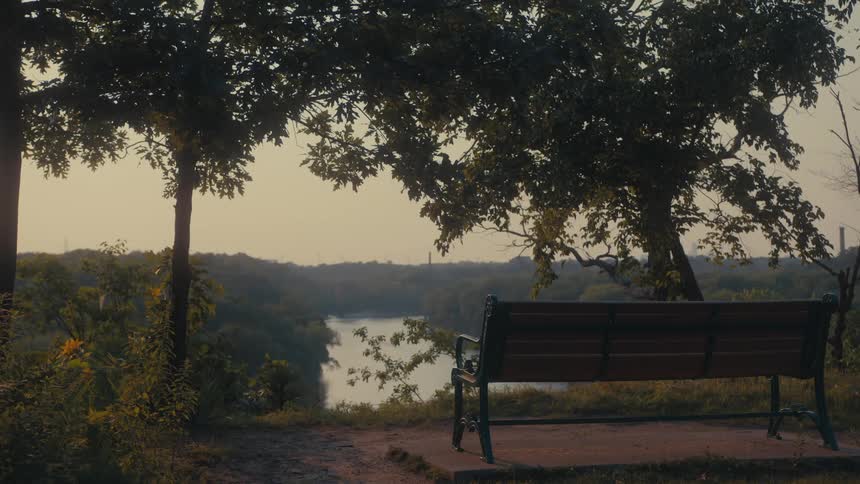 Landscape of a wooden bench on a wooded hill with a river in the background