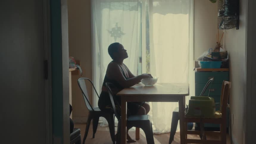 Woman sits at a table at home and soaks her fingers in a solution