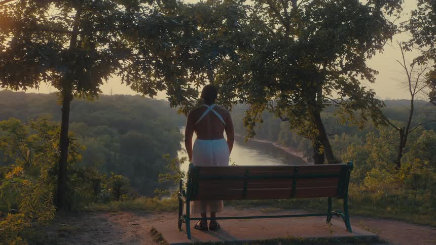A woman gets up from the bench over the river
