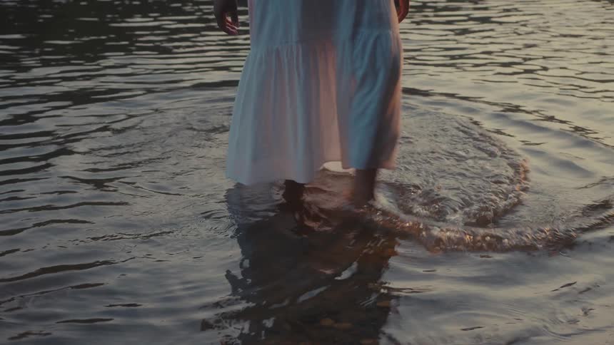 A woman kicks the water around as she walks