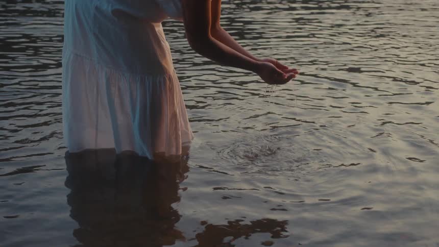Woman in wet white dress in a lake