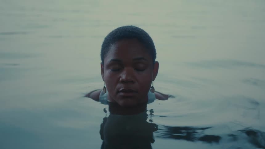 Woman submerged to her neck wears dangling earrings