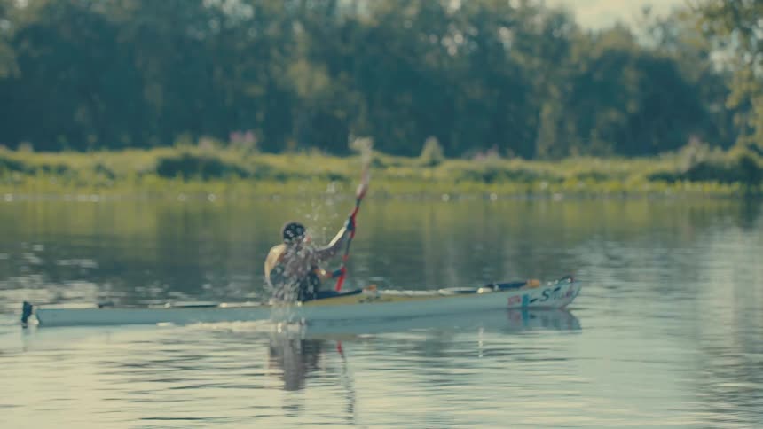 Person actively performing canoeing on a river with vegetation in the background