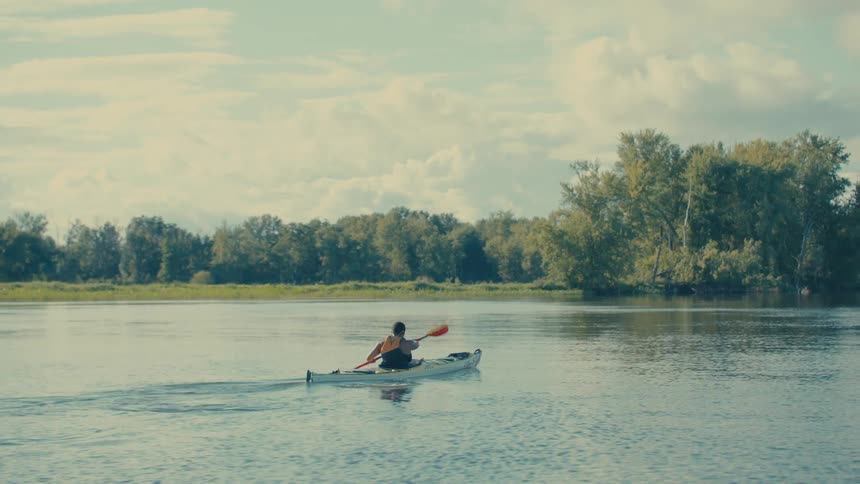 Lone canoeist glides calmly over the calm waters of a mirrorlike river