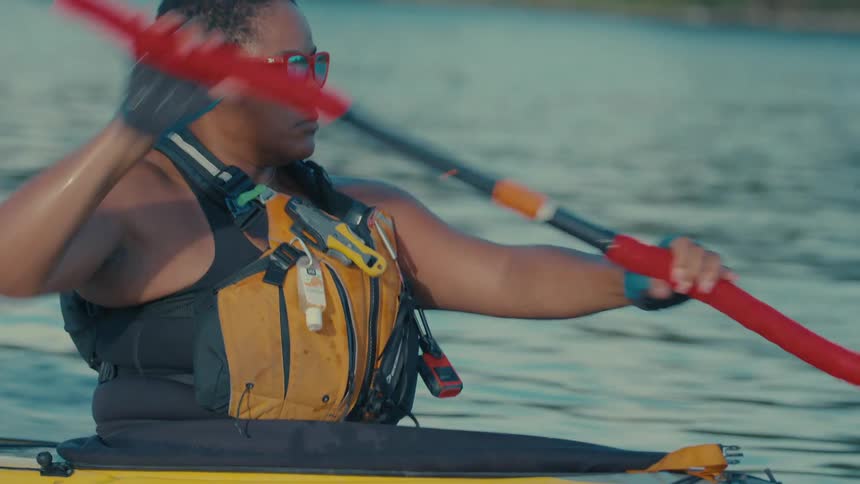 A woman is paddling fast on the lake in her kayak