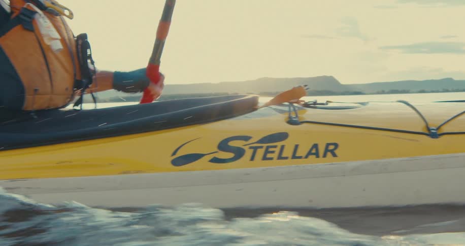Closeup of a person paddling a yellow kayak